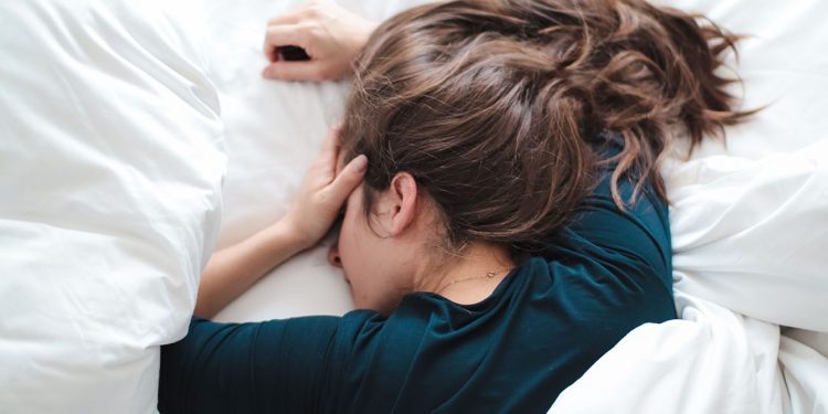 Woman lying in bed with a headache