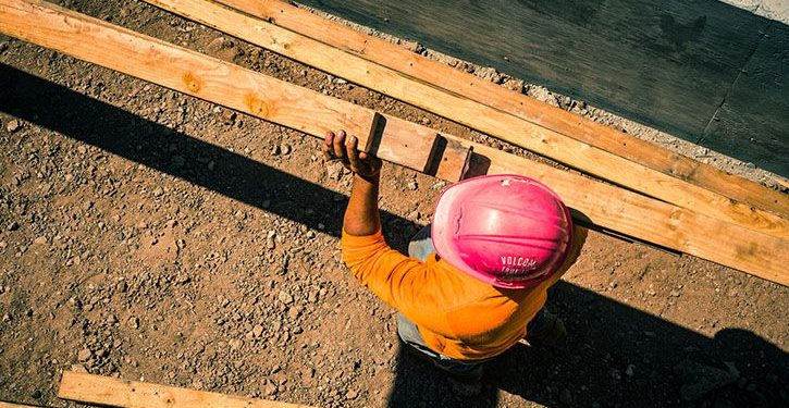 Worker at a construction site carrying wood blocks
