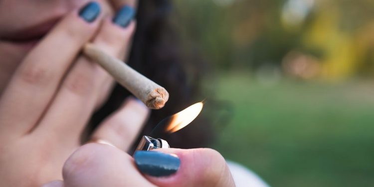 A young person lighting a cannabis joint