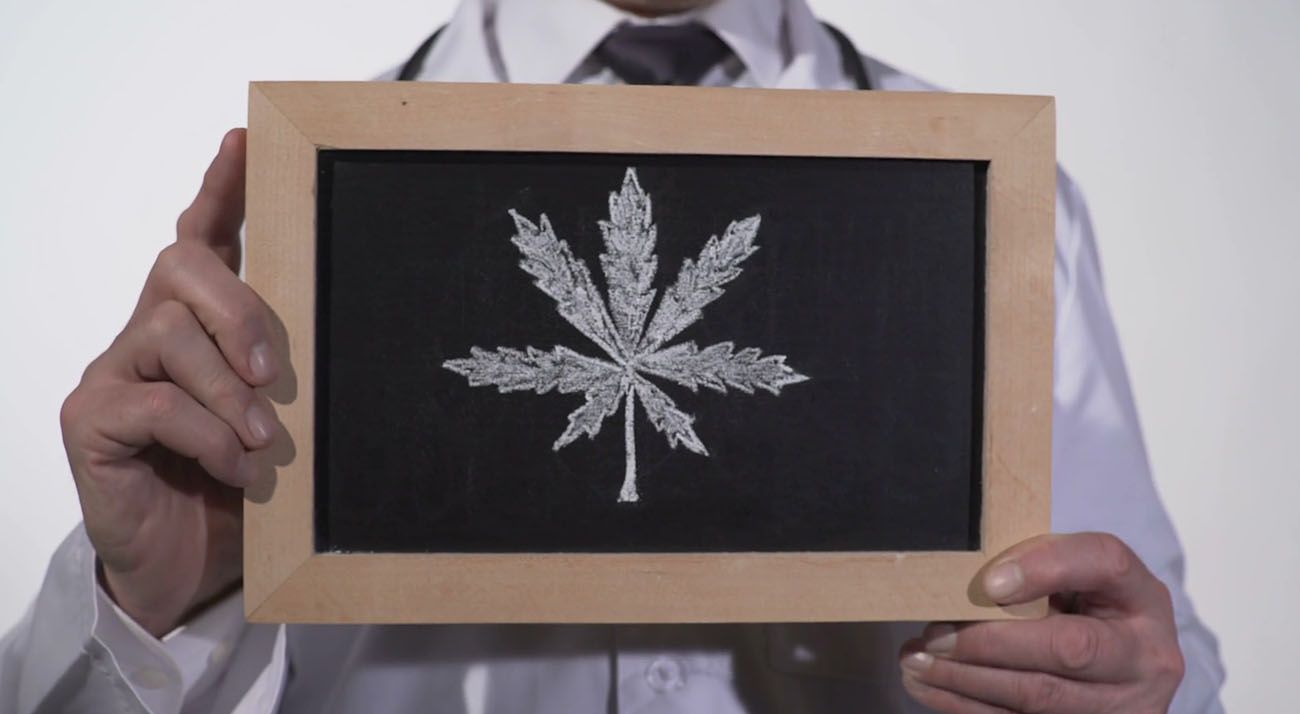 Doctor hold cannabis leaf drawn on chalkboard